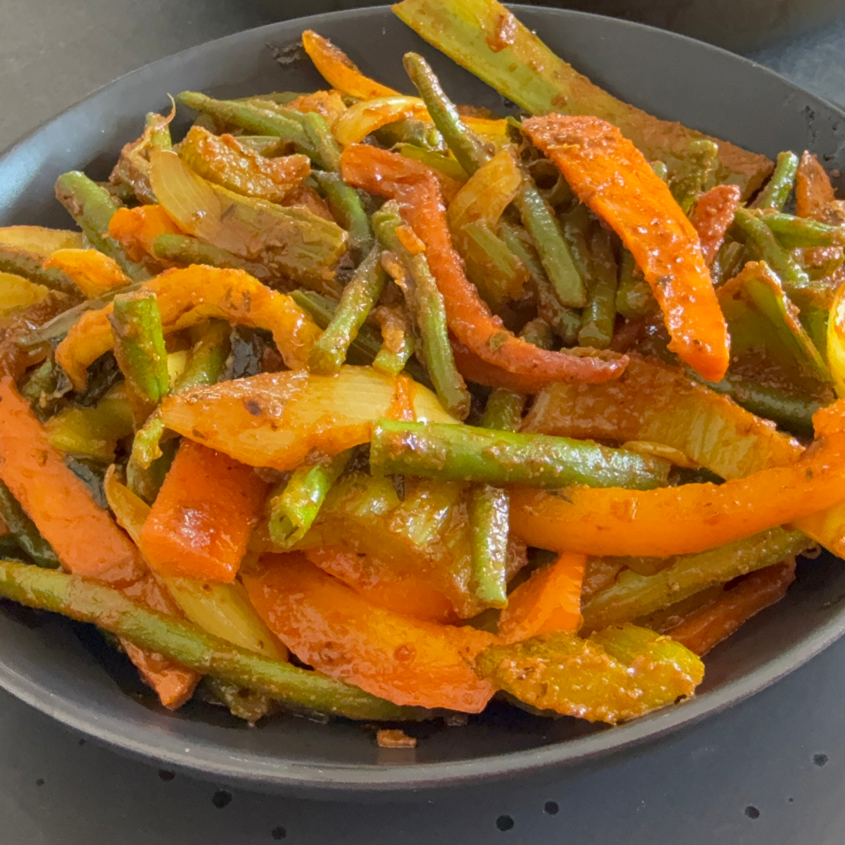 Bunte vegane Gemüsepfanne mit grünen Bohnen, Stangensellerie, Karotten und Paprika auf einem tiefen Teller