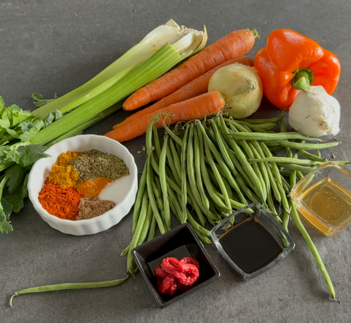 Zutaten für eine vegane Gemüsepfanne mit grünen Bohnen, Stangensellerie, Karotten, Paprika, Zwiebel und Knoblauch