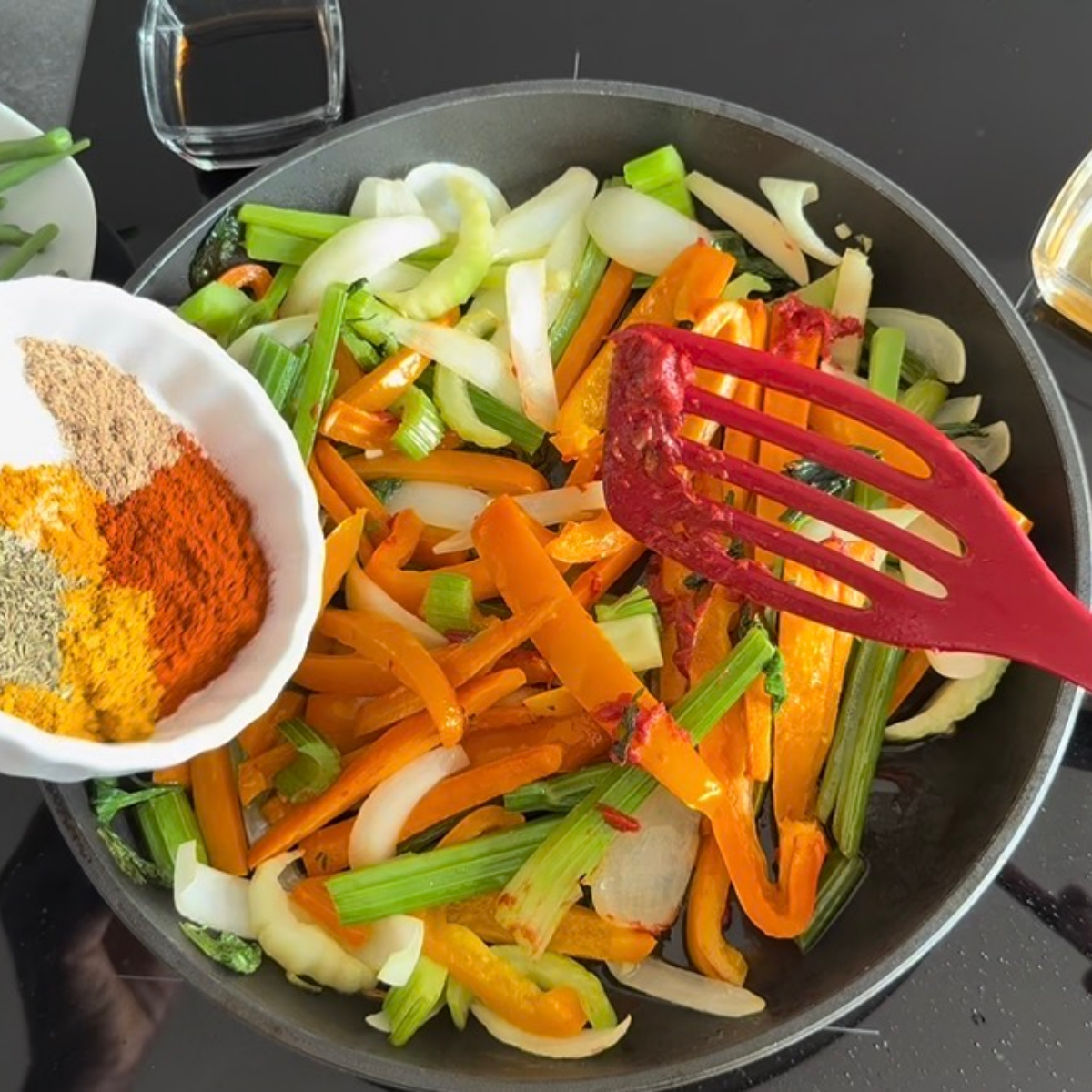 Gewürze und Tomatenmark werden zum Gemüse in die Pfanne gegeben und untergerührt