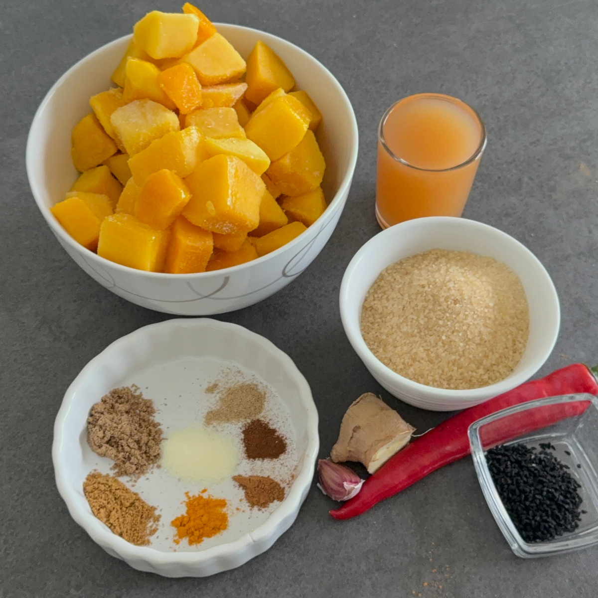Zutaten für Mango-Chutney mit aufgetauter Mango, Ingwer, Knoblauch, Chili und Gewürzen.