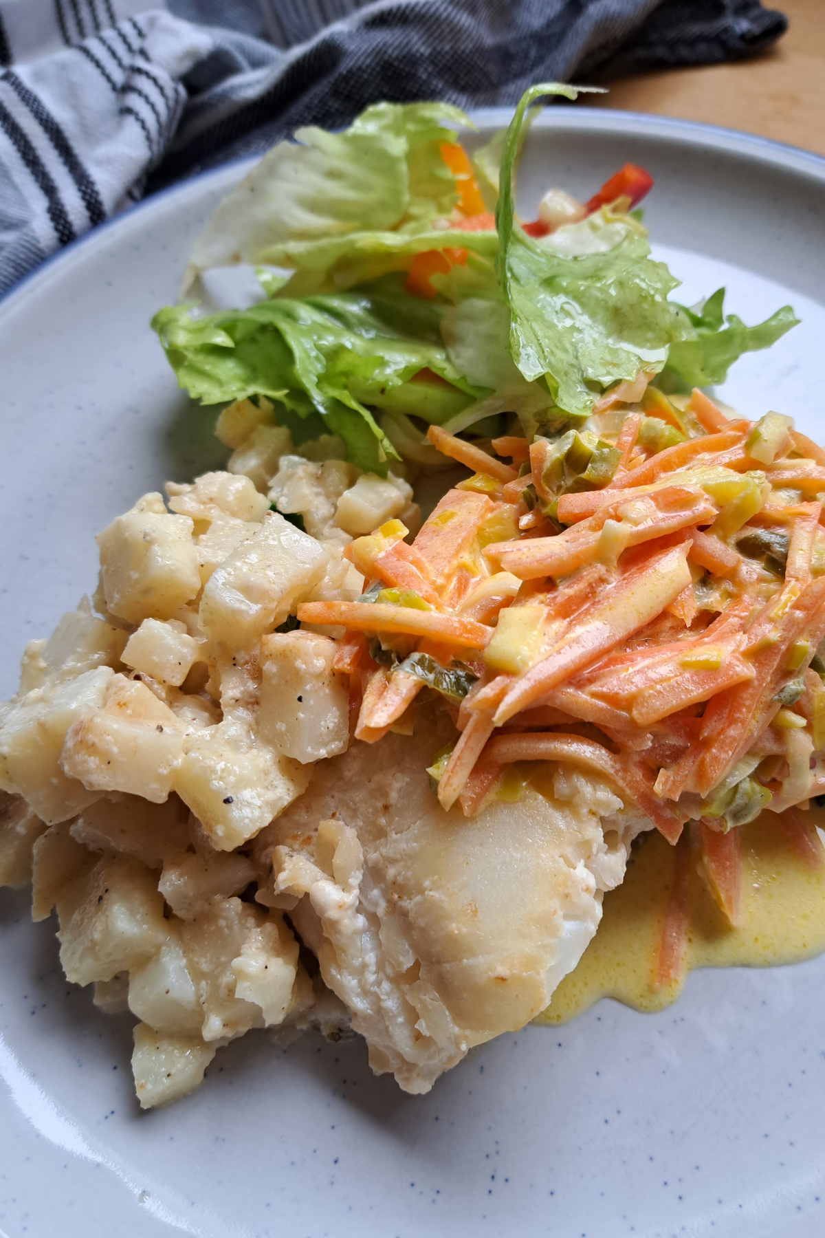 Selleriegemüse mit Sahne und Butter, serviert mit Skrei, grünem Salat und Möhrengemüse